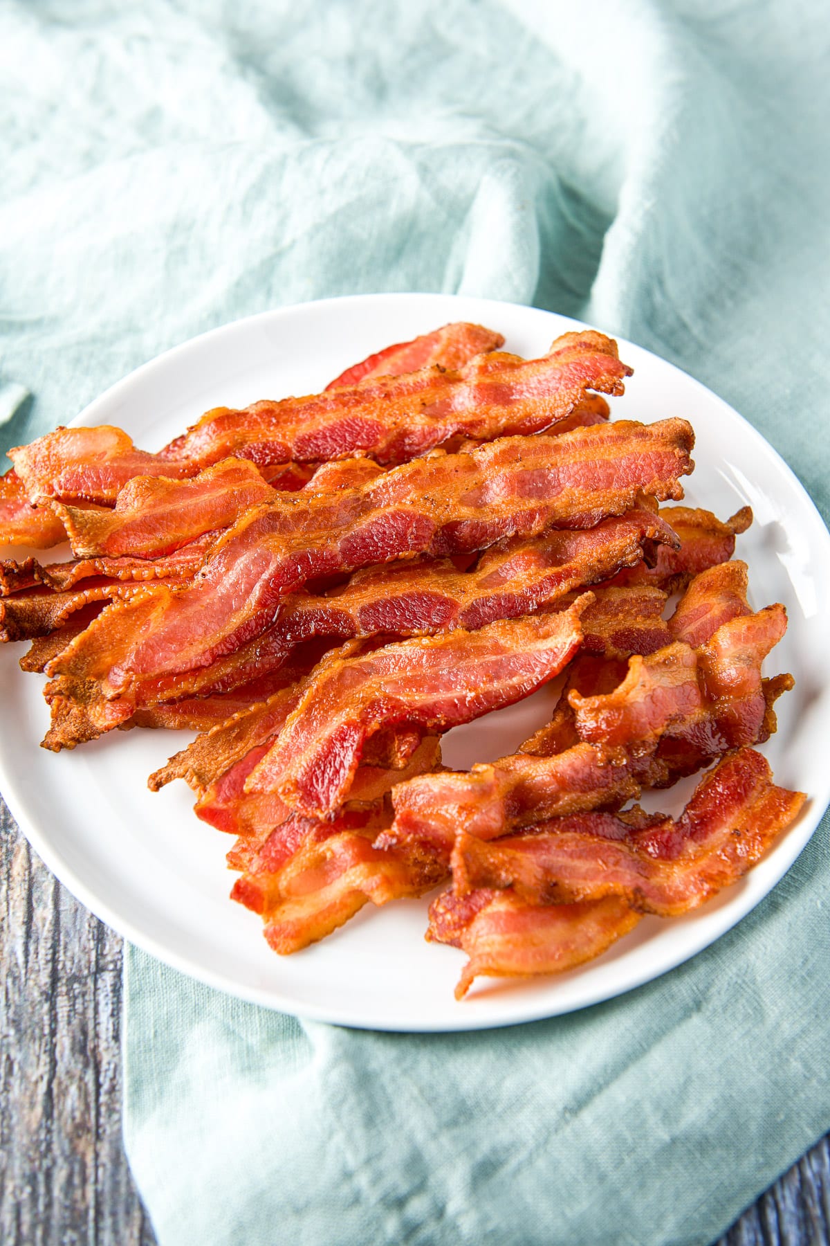 A higher view of a white plate with cooked bacon on it