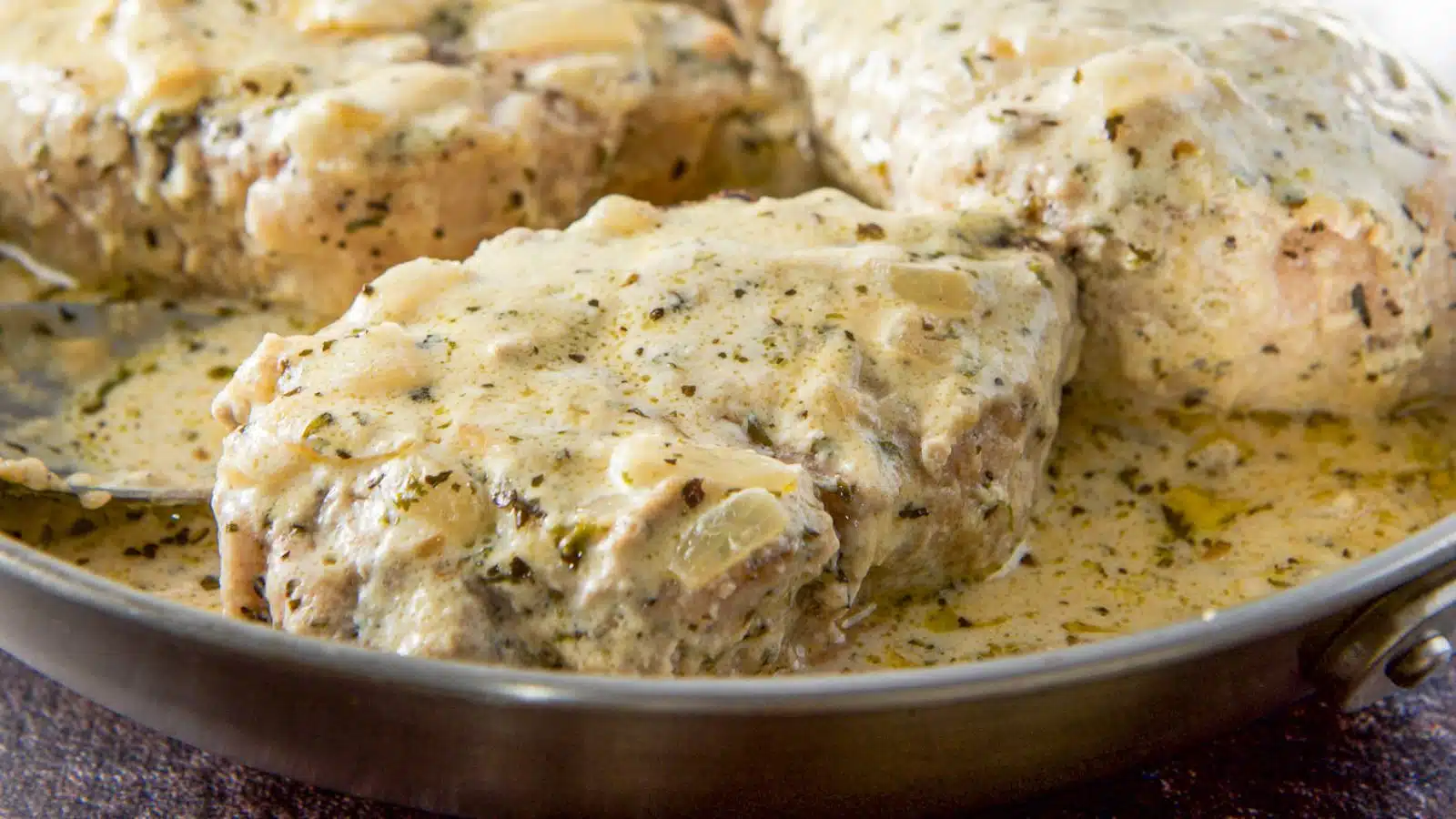 a pan with pork chops in it with a creamy sauce on them