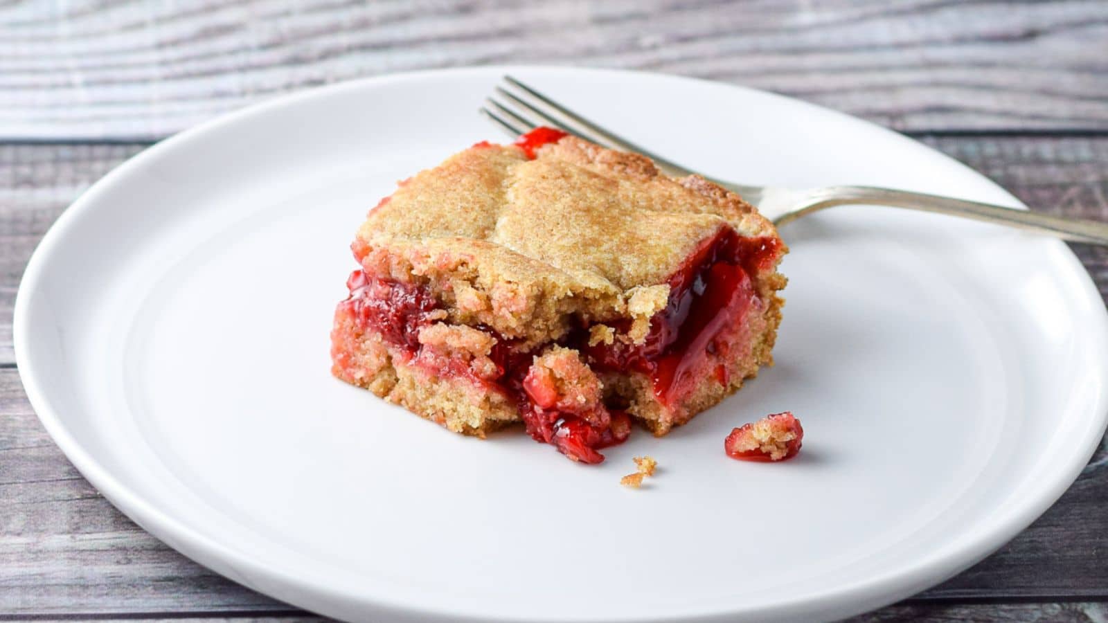 a white plate with a cherry dessert on it and a fork