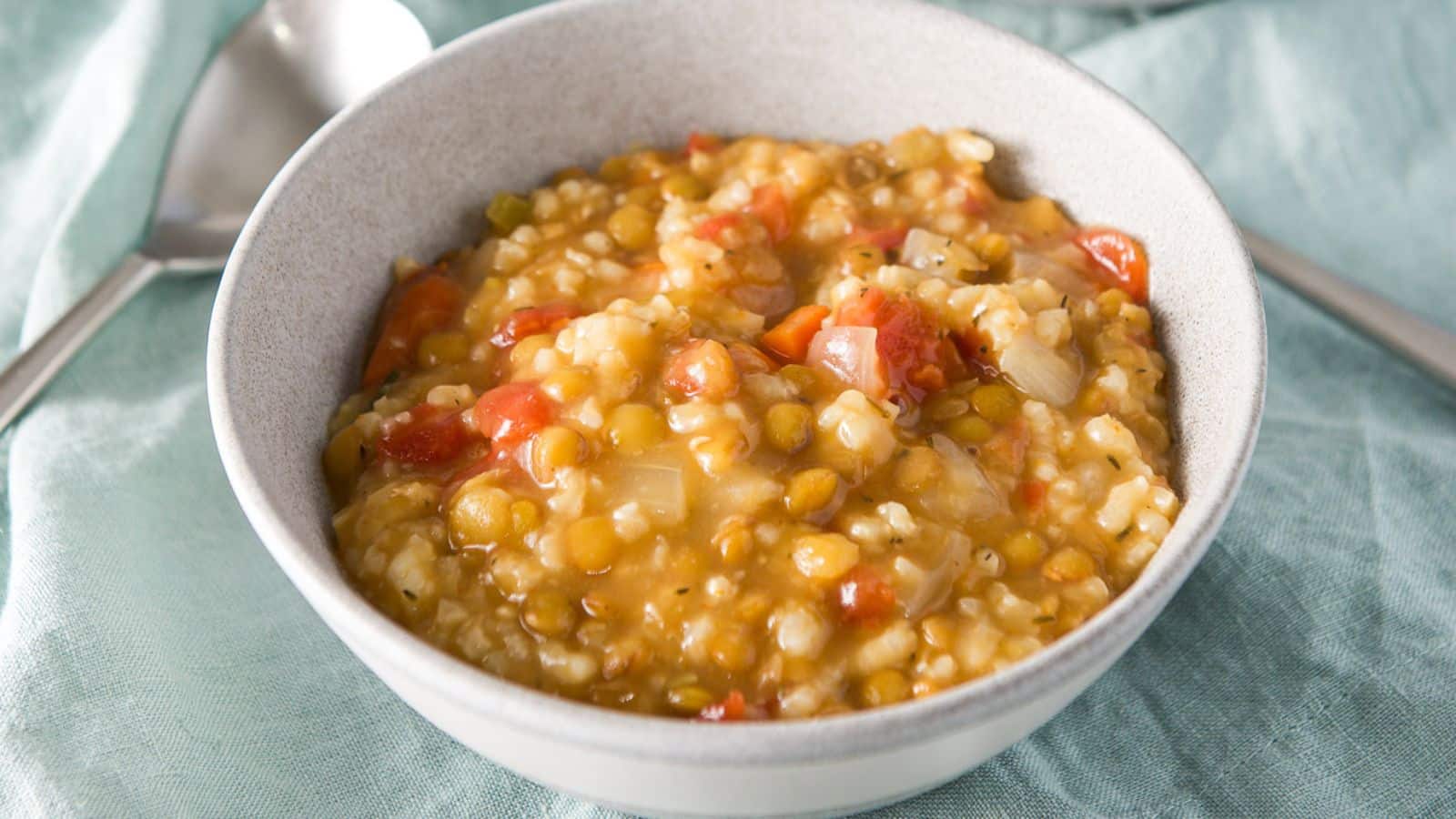 a grey bowl filled with lentil and rice soup on a green napkin