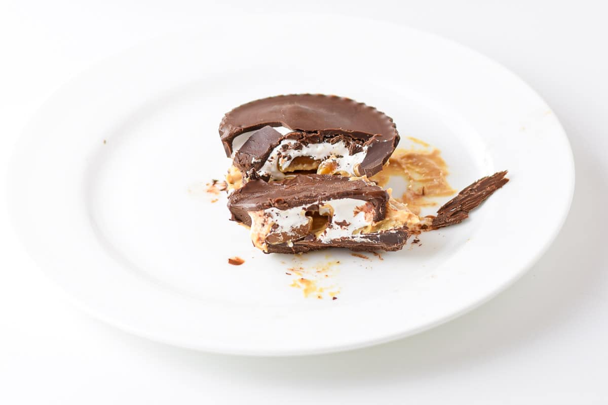 A white plate with marshmallow cups on it with caramel and peanut butter