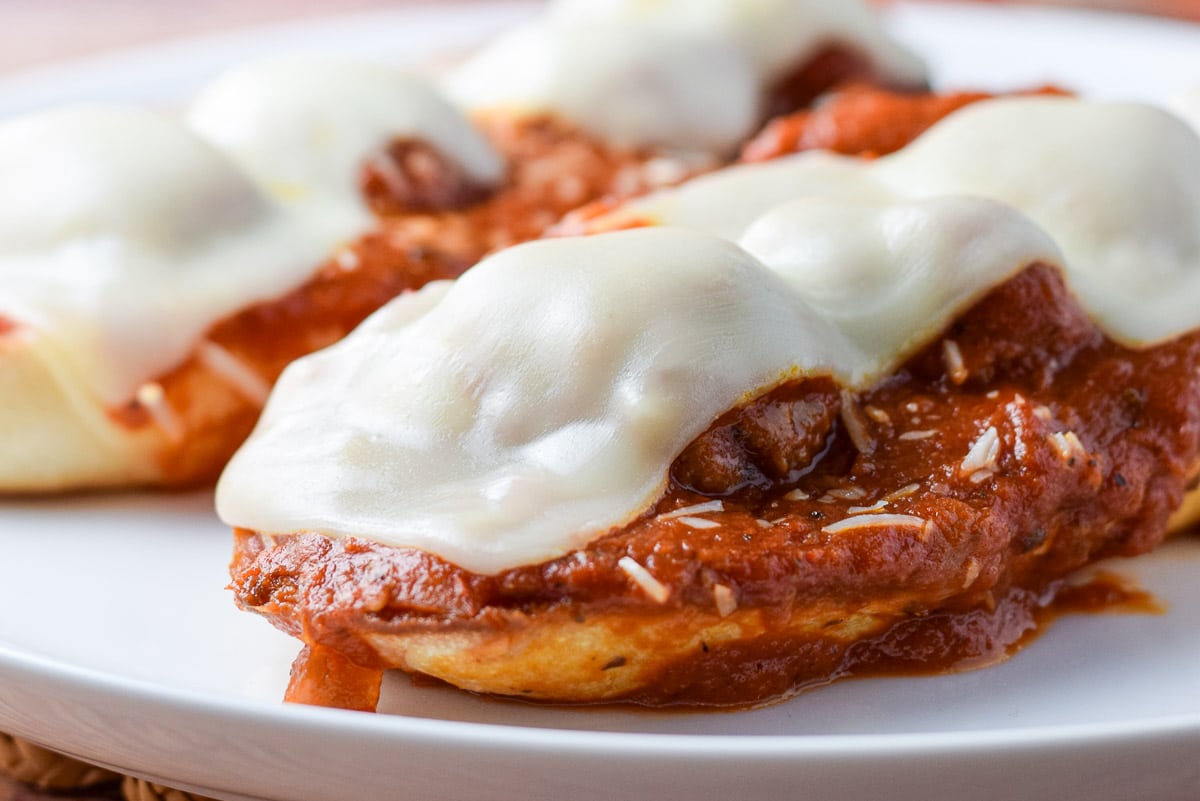 featured photo of a closeup of cheese melted on a meatball sub on a white plate