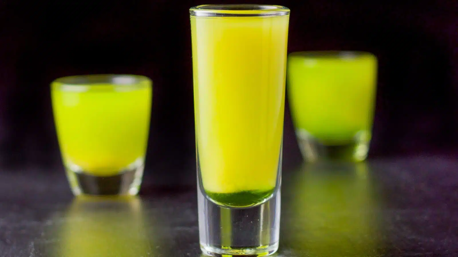 three shot glasses filled with the green and yellow shot