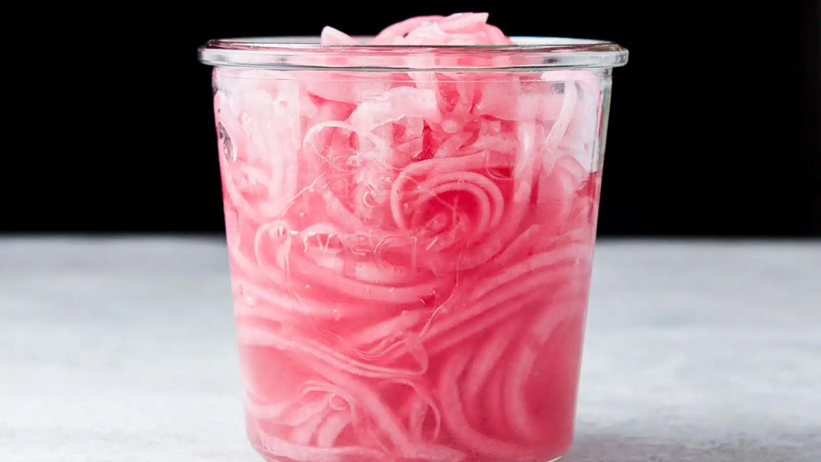 An open jar with Mexican pickled onions in it along with juice