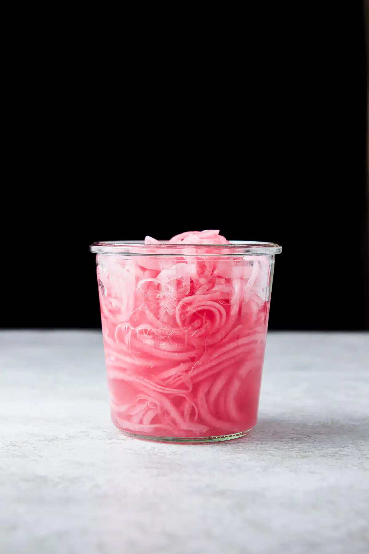 vertical view of a glass jar with pickled onions in it