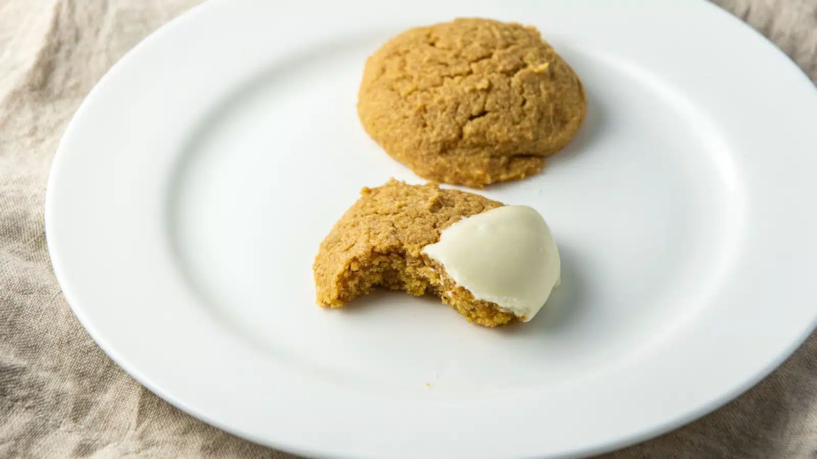 two cookies, one with a bite taken out of it on a plate