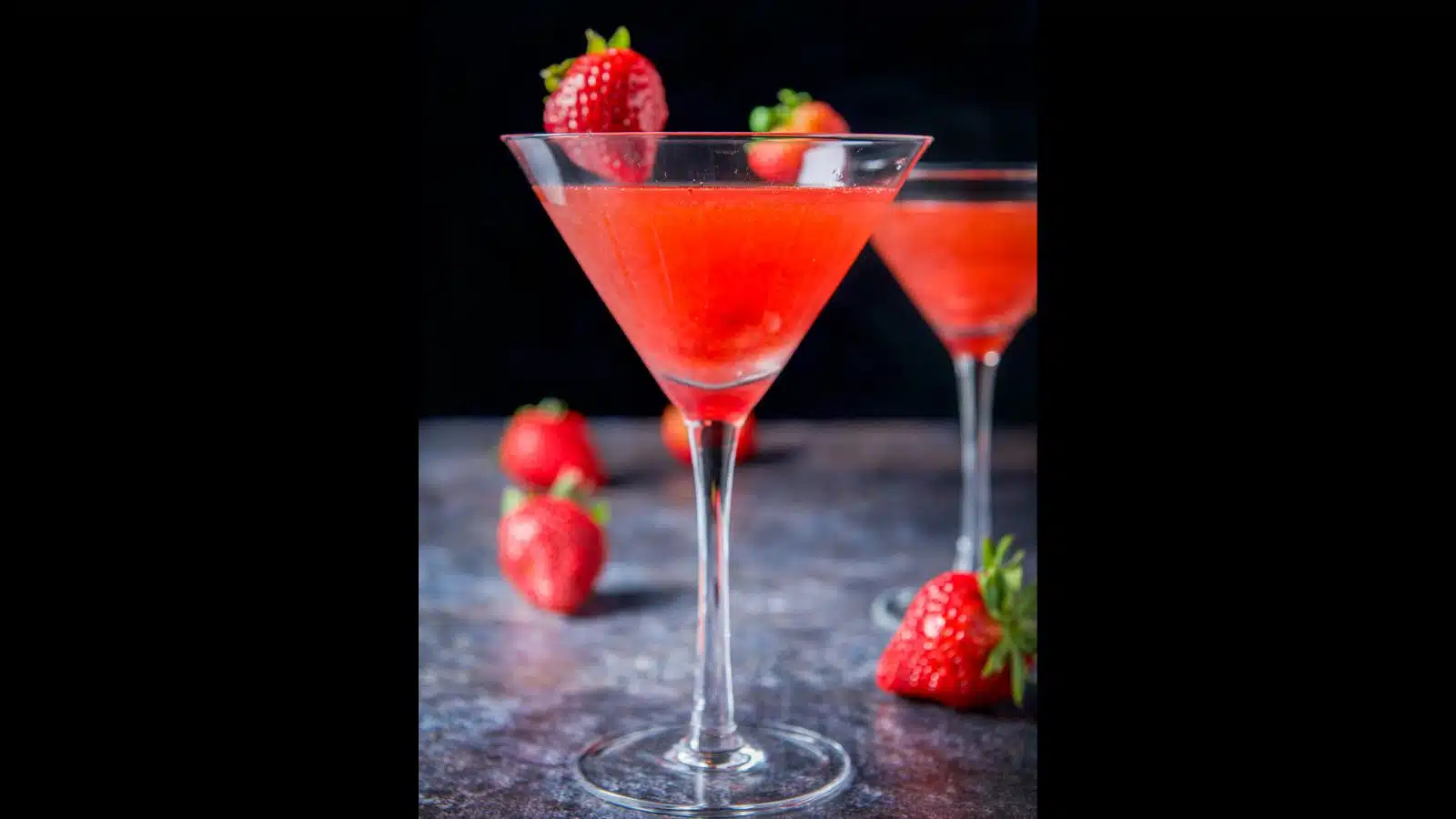 Two martini glasses filled with the strawberry drink with strawberries as garnish