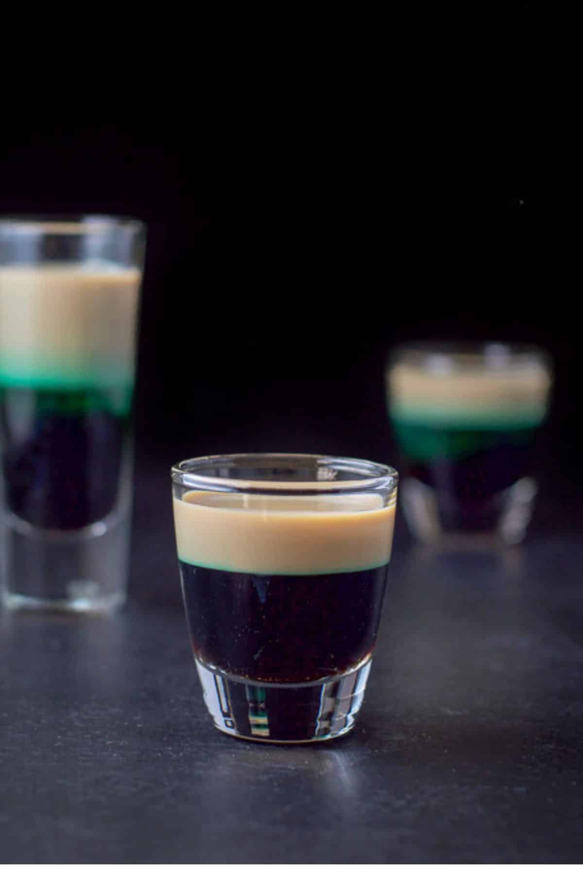 Vertical view of the short glass filled with the shot and the other two glass in the background