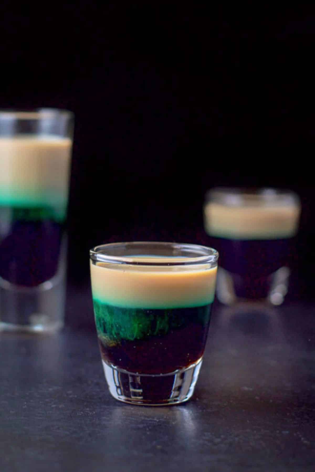 Another view of the short glass showing the green leeching in the Baileys with the other two glasses in the background