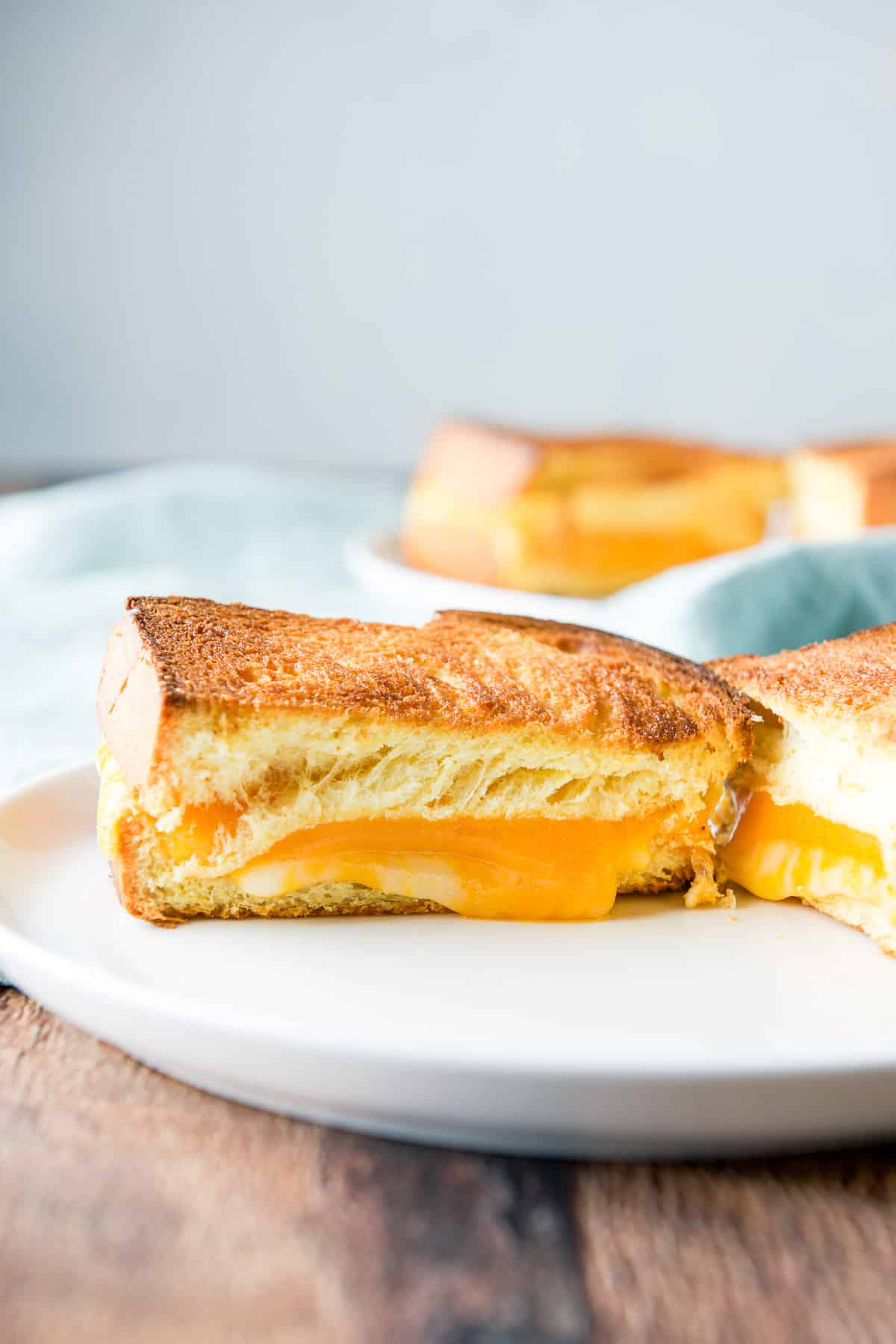 A white plate with melted cheese between two pieces of bread cut in half