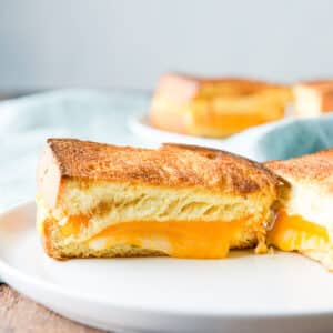 square photo of a white plate with a melted cheese in bread