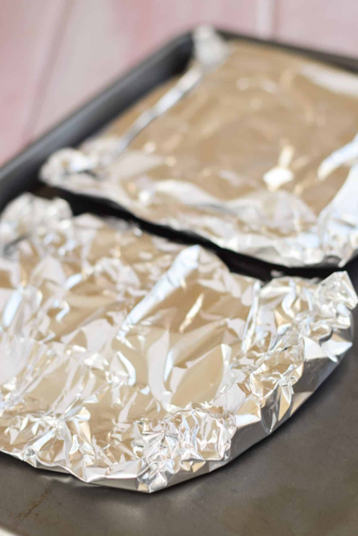 Vegetables are tucked inside foil and placed on a jelly roll pan