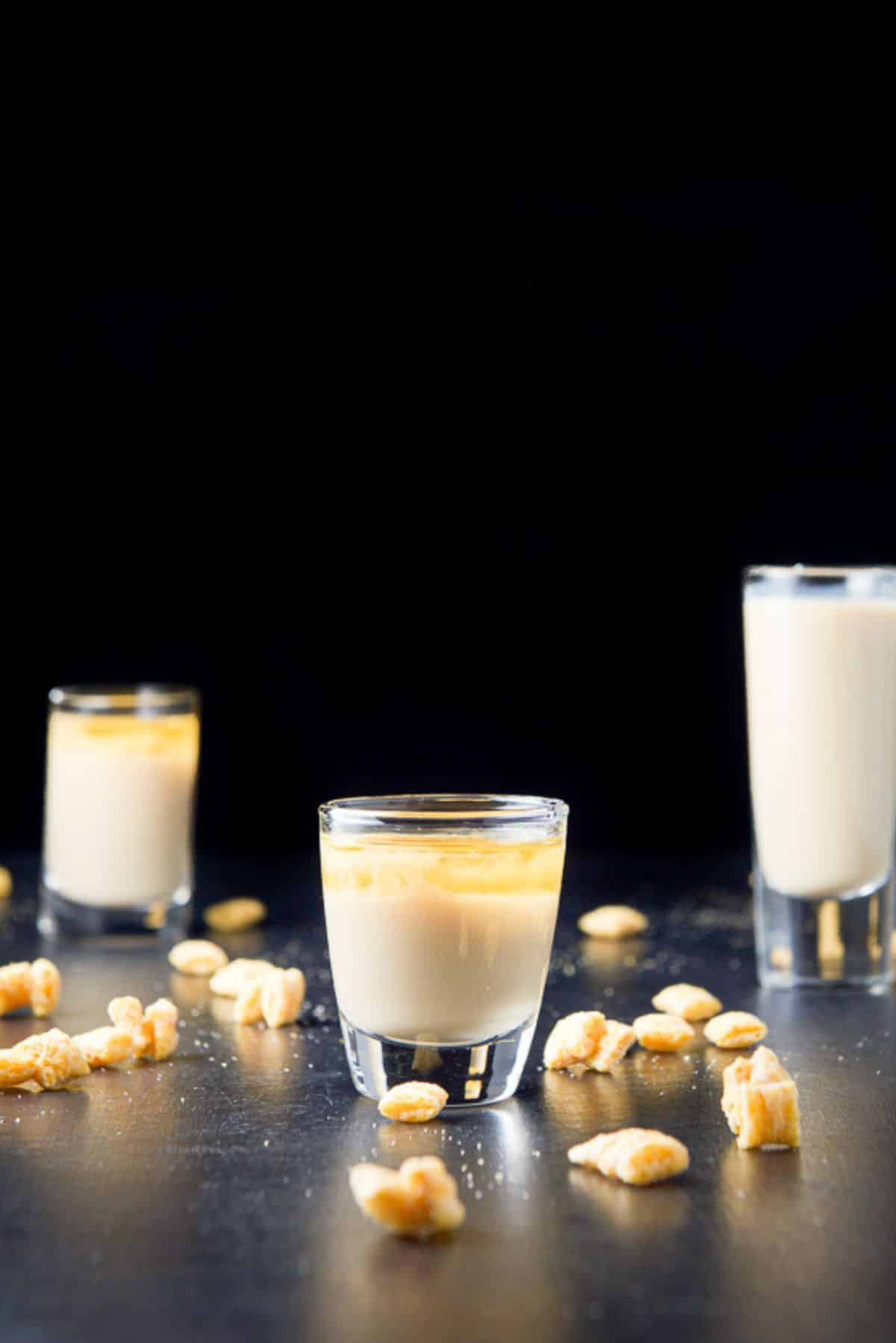 Vertical view of the short glass filled with the layered shot with two other glasses in the background