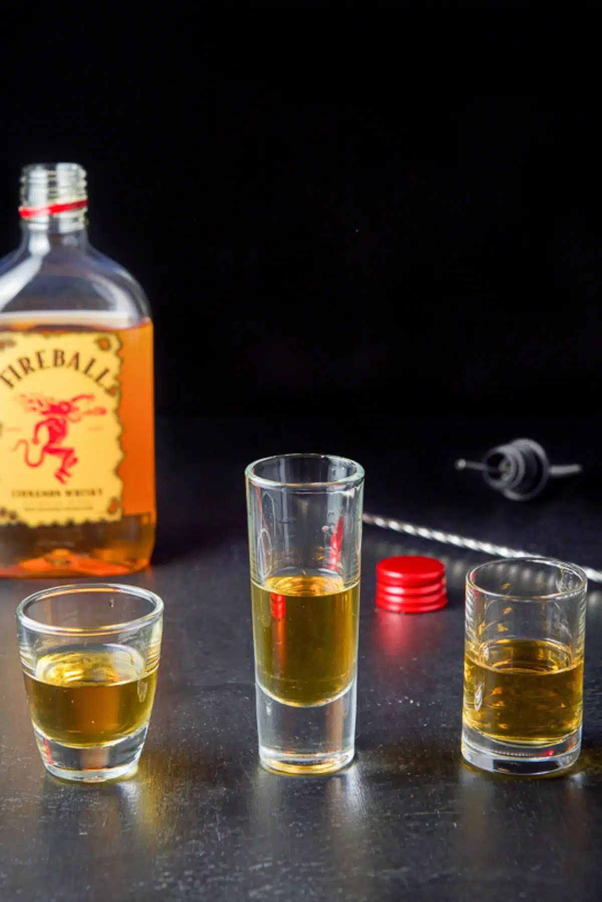 Fireball whiskey poured in the three shot glasses with the whiskey in the background