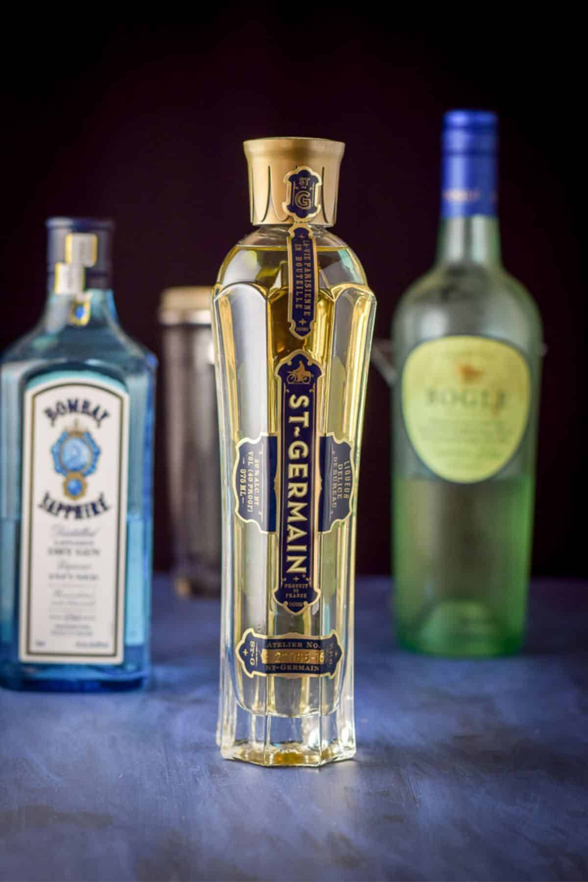 St Germain, gin and wine on a table with a cocktail shake and martini glass