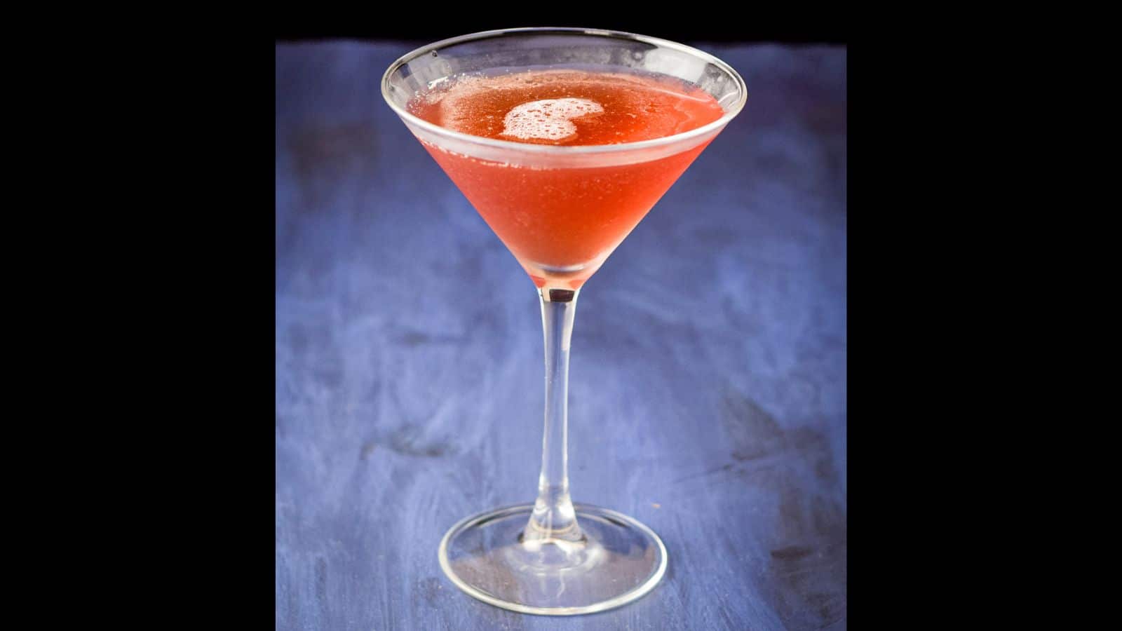 Closer view of the Ch&acirc;telaine drink on a blue table and black background