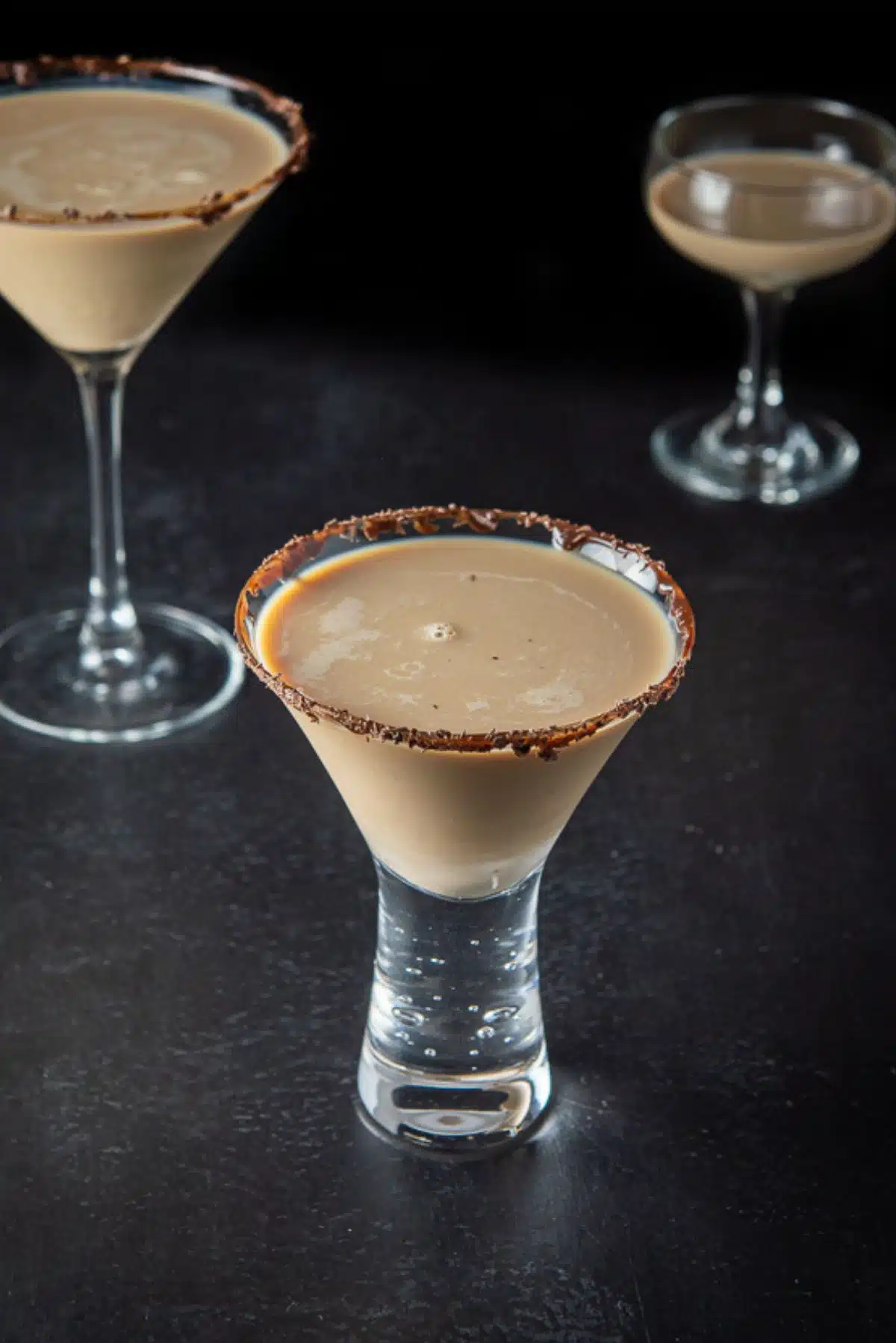 The short glass with chocolate martini in it in front of two other filled glasses
