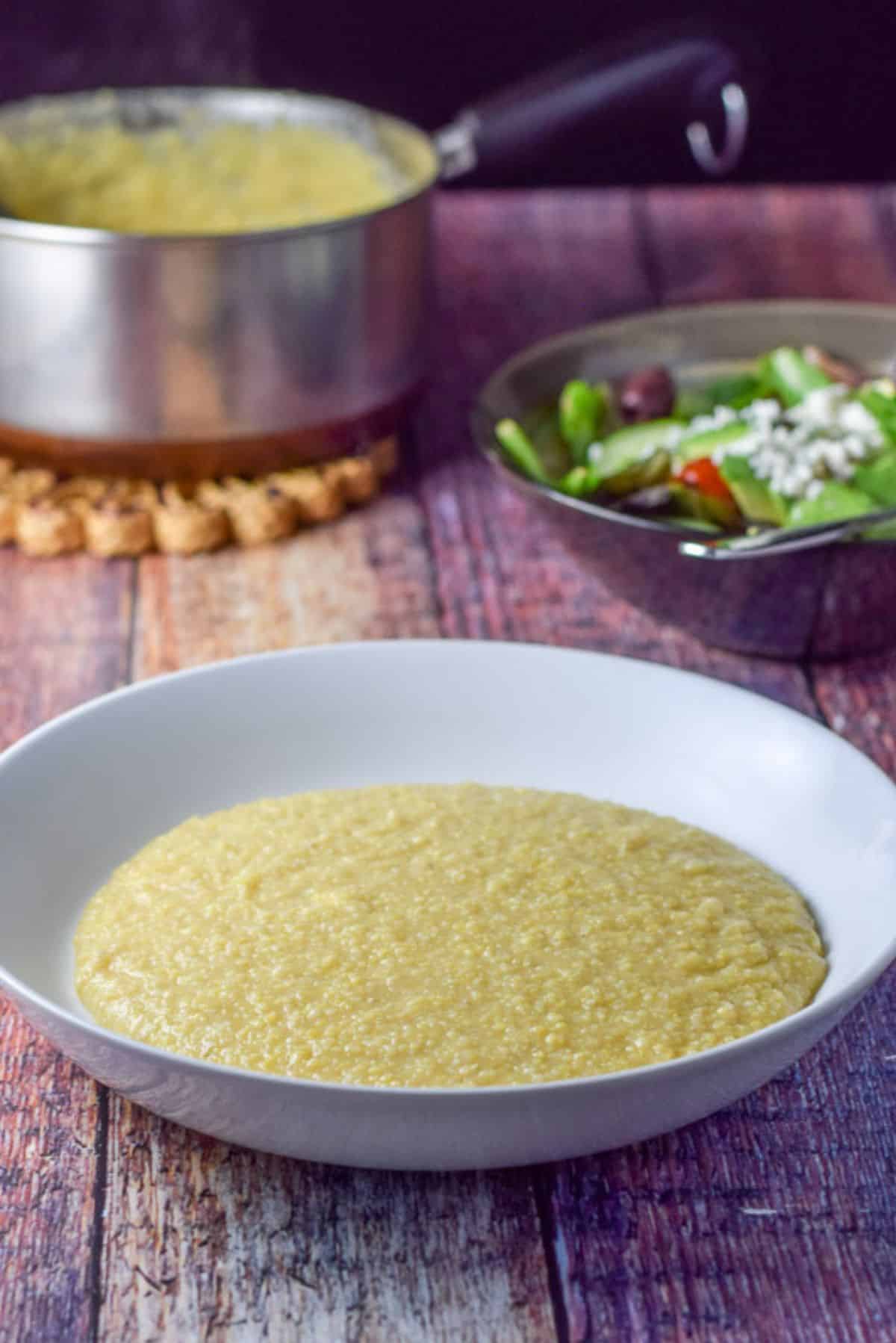 Polenta cooked, a salad and the pan of polenta in the background