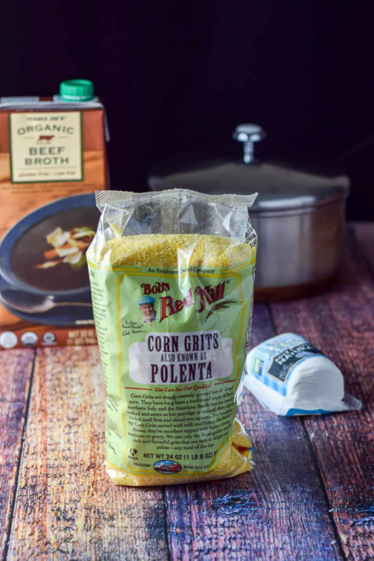 Polenta, beef broth and mozzarella on a wooden table along with a pot