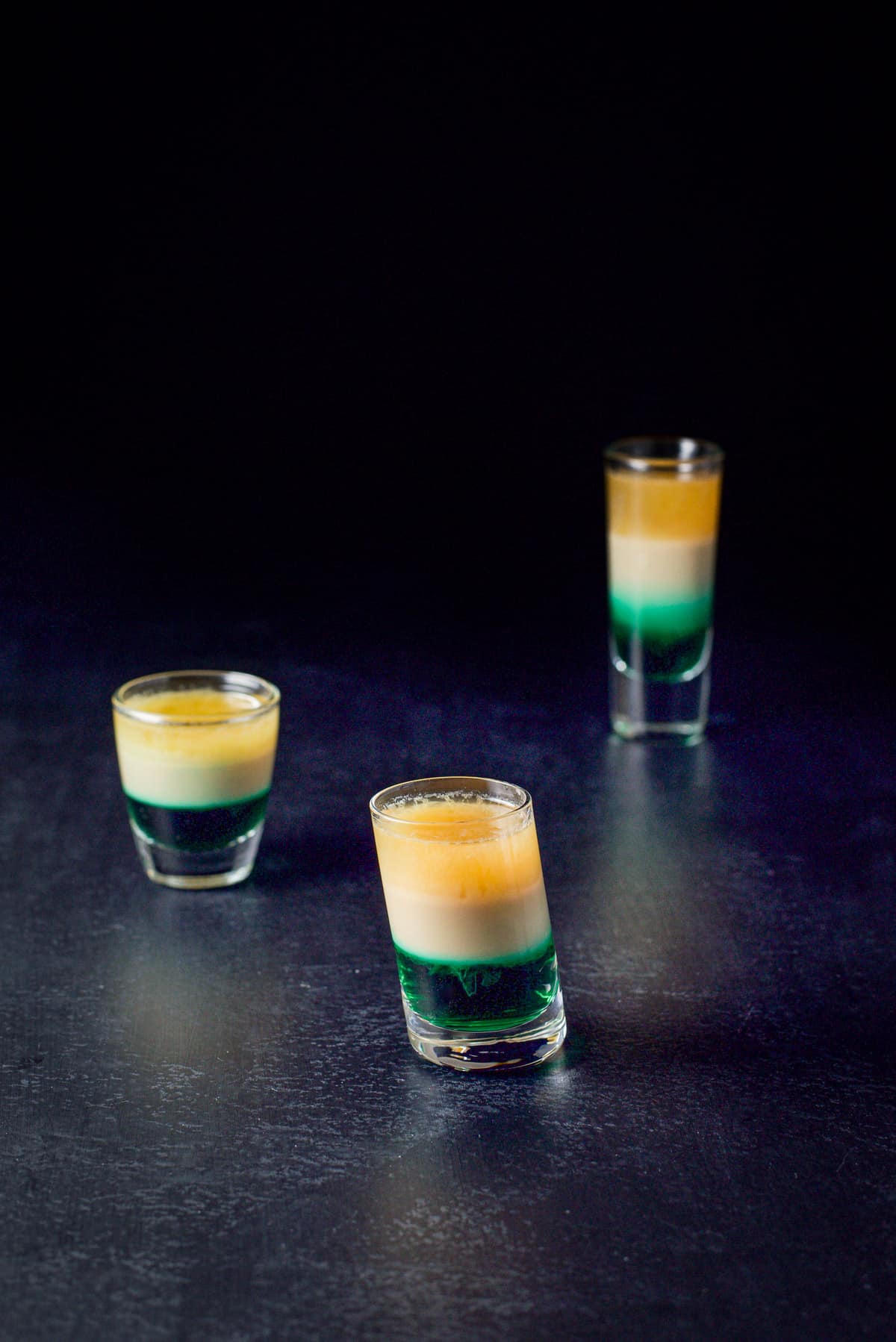 An upper view of the three layered shot in the tilted glass in front of the two other glasses