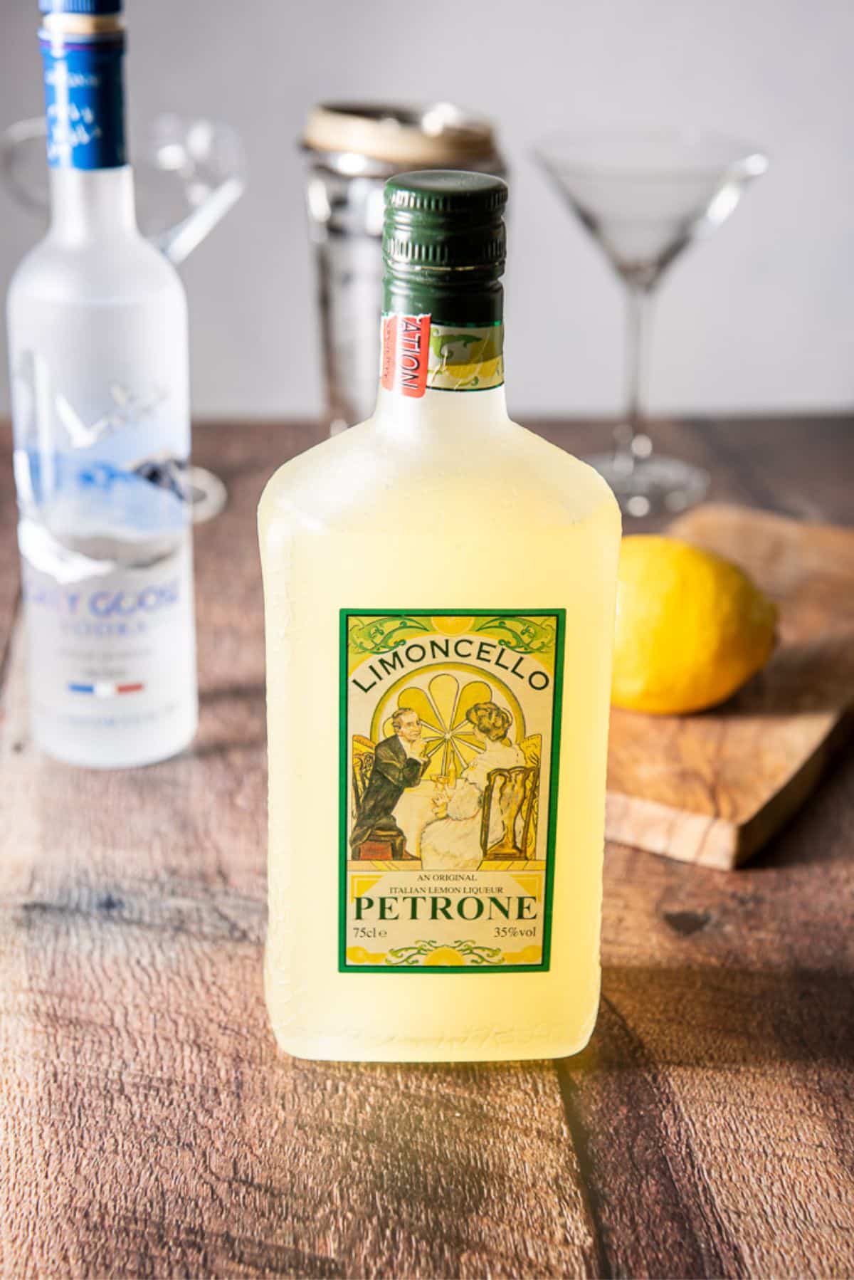 a table with limoncello, vodka, lemon and glasses and shaker