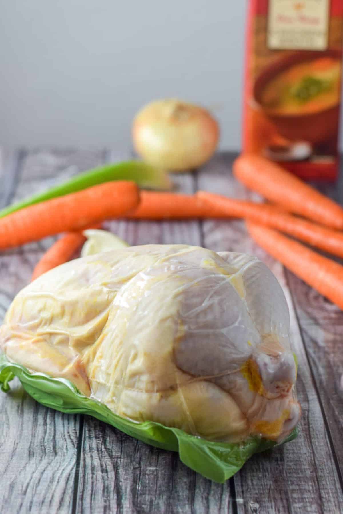 Organic whole chicken all wrapped up, carrots, celery and an onion for the chicken soup