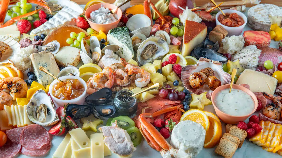 seafood, cheese, bread, sauces, and fruit on a board