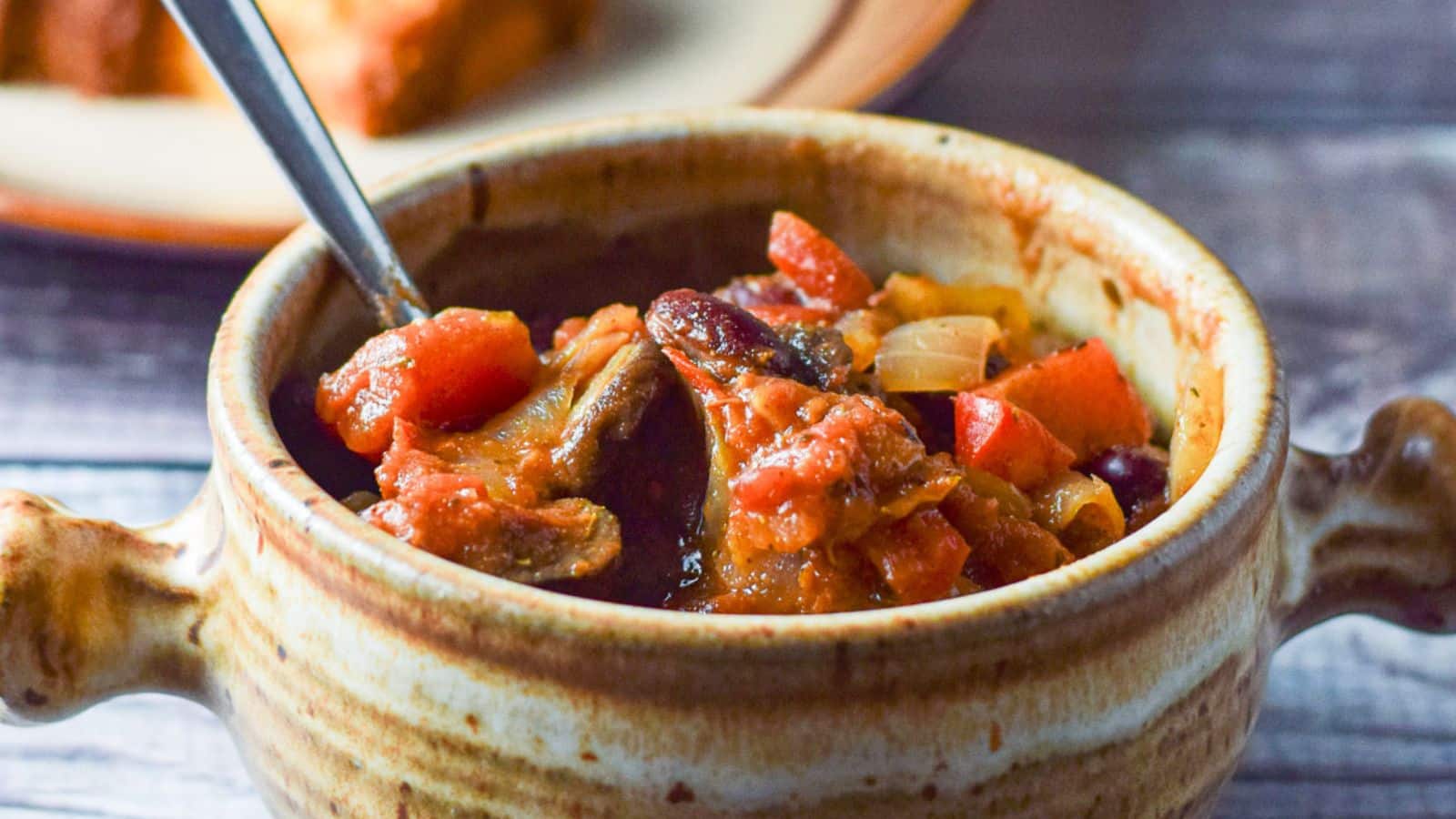 Close up of a crock with chili in it along with a spoon