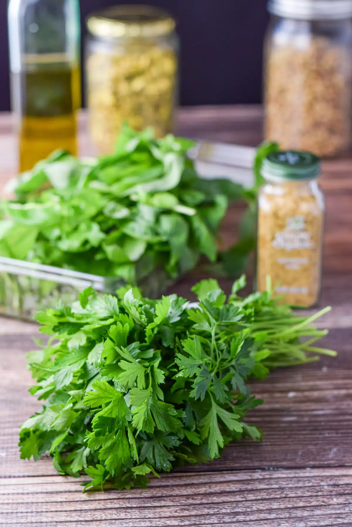 Fresh parsley, basil, nutritional yeast, pistachios, and oil on the table