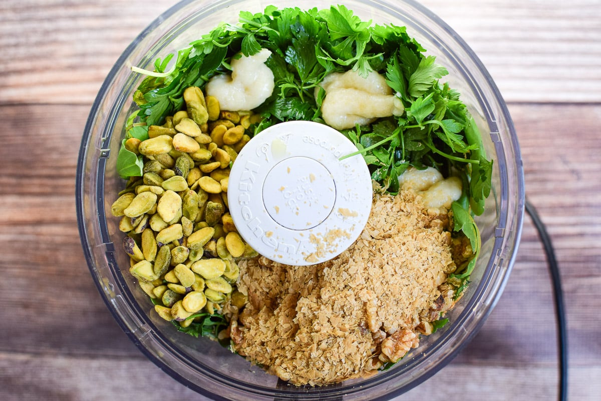 Overhead view of the food processor container with the ingredients for the pesto in it