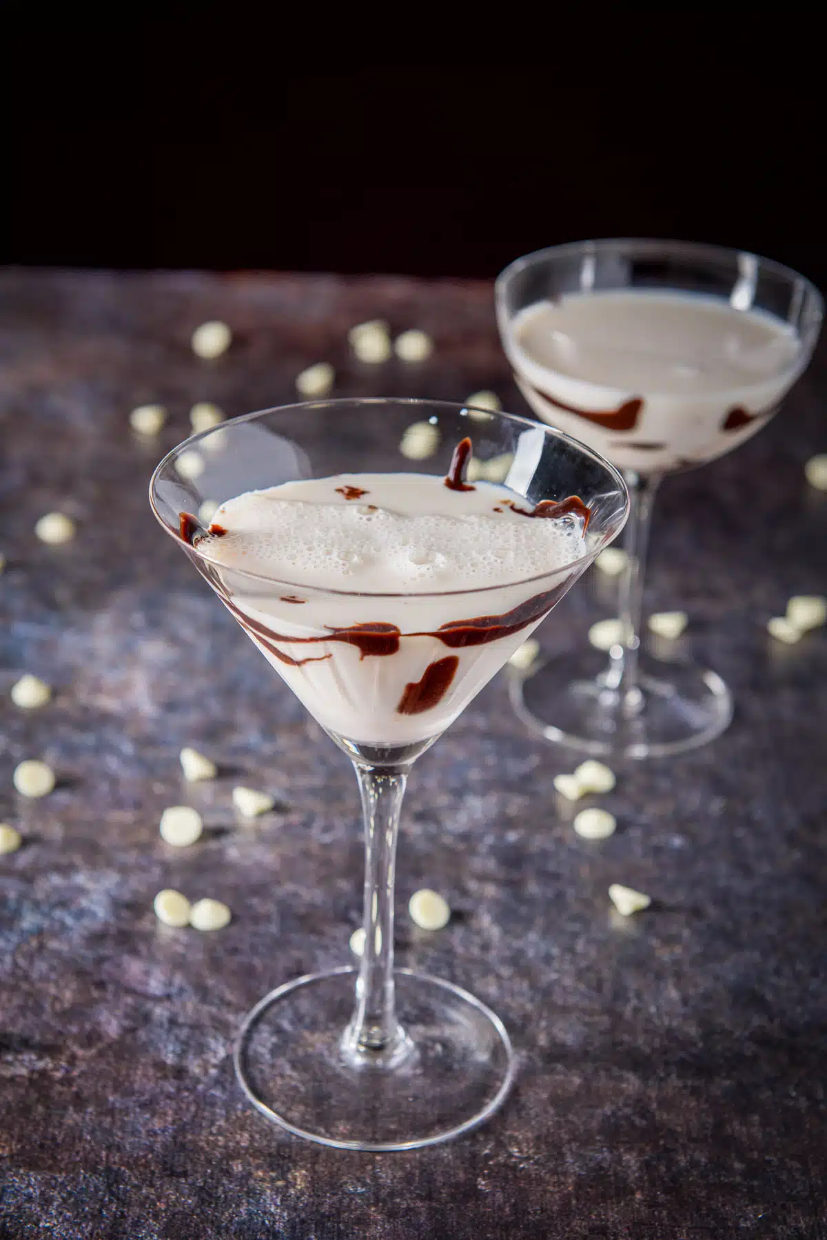 Classic martini glass filled with a milky cocktail with chocolate chips on the table