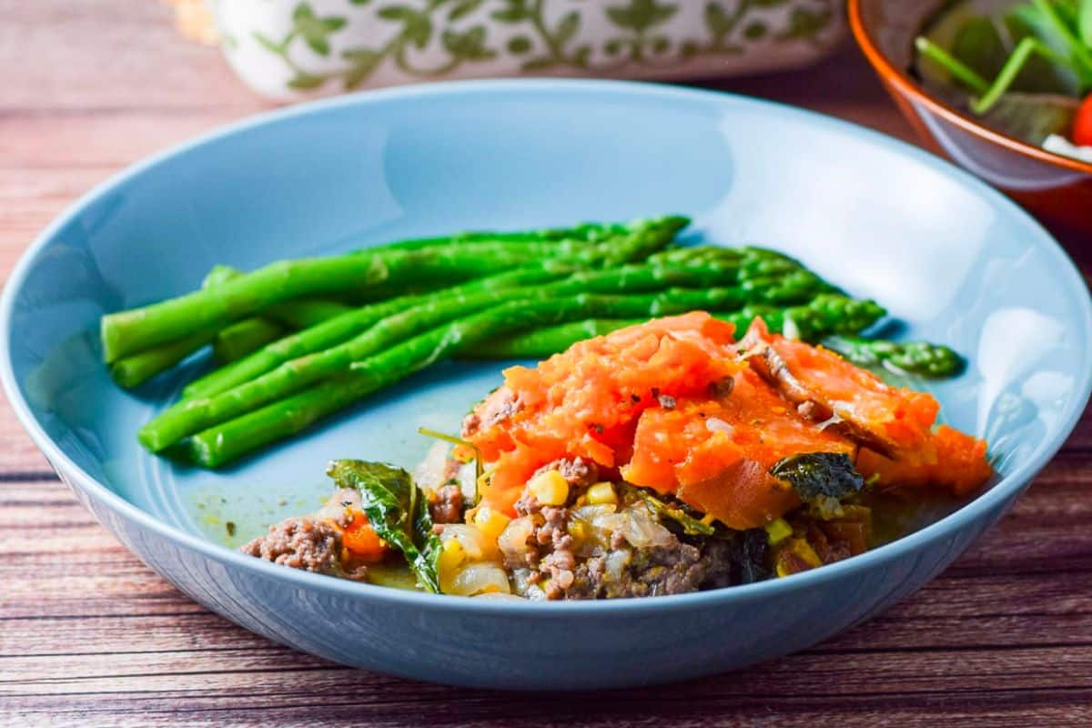 Shepherd's pie casserole on a plate with veggies on the side.
