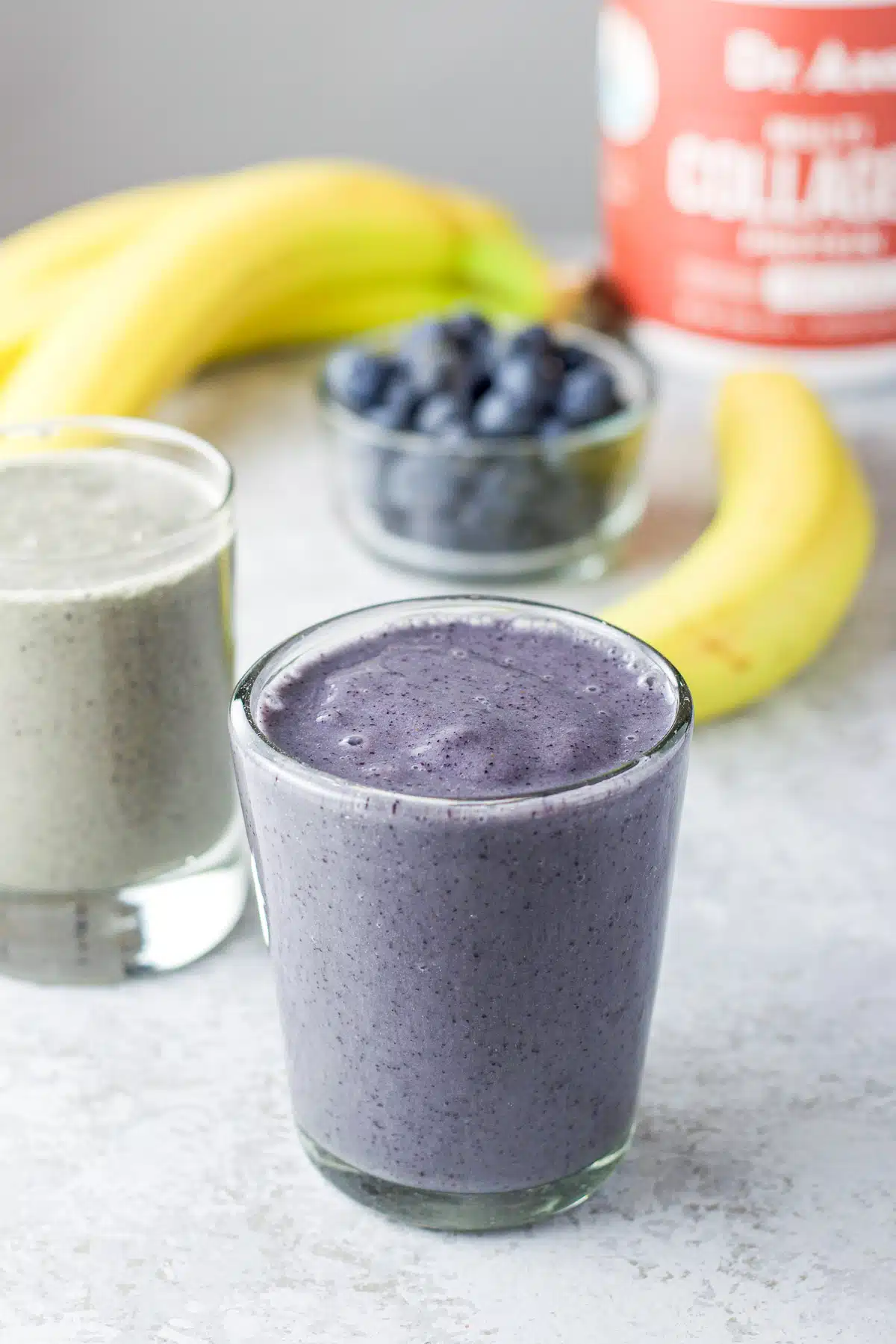 Close up of the blueberry smoothie with blueberries, bananas and collagen in the background