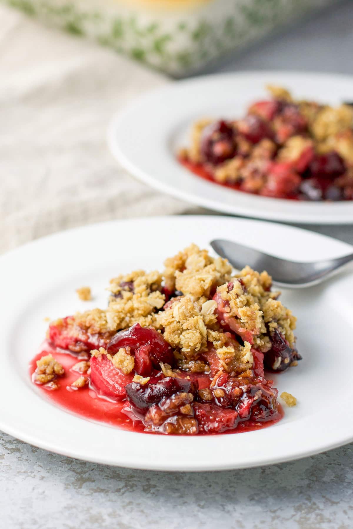 Two white plates with the cherry, rhubarb dessert on it