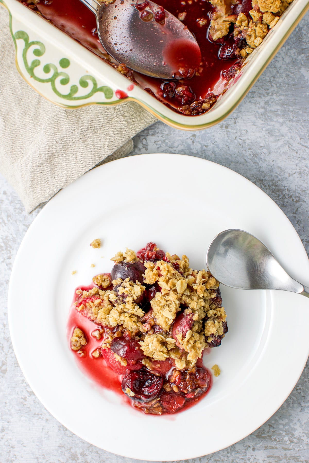 Overhead view of a white plate with the cherry dessert on it along with the pan in the upper portion