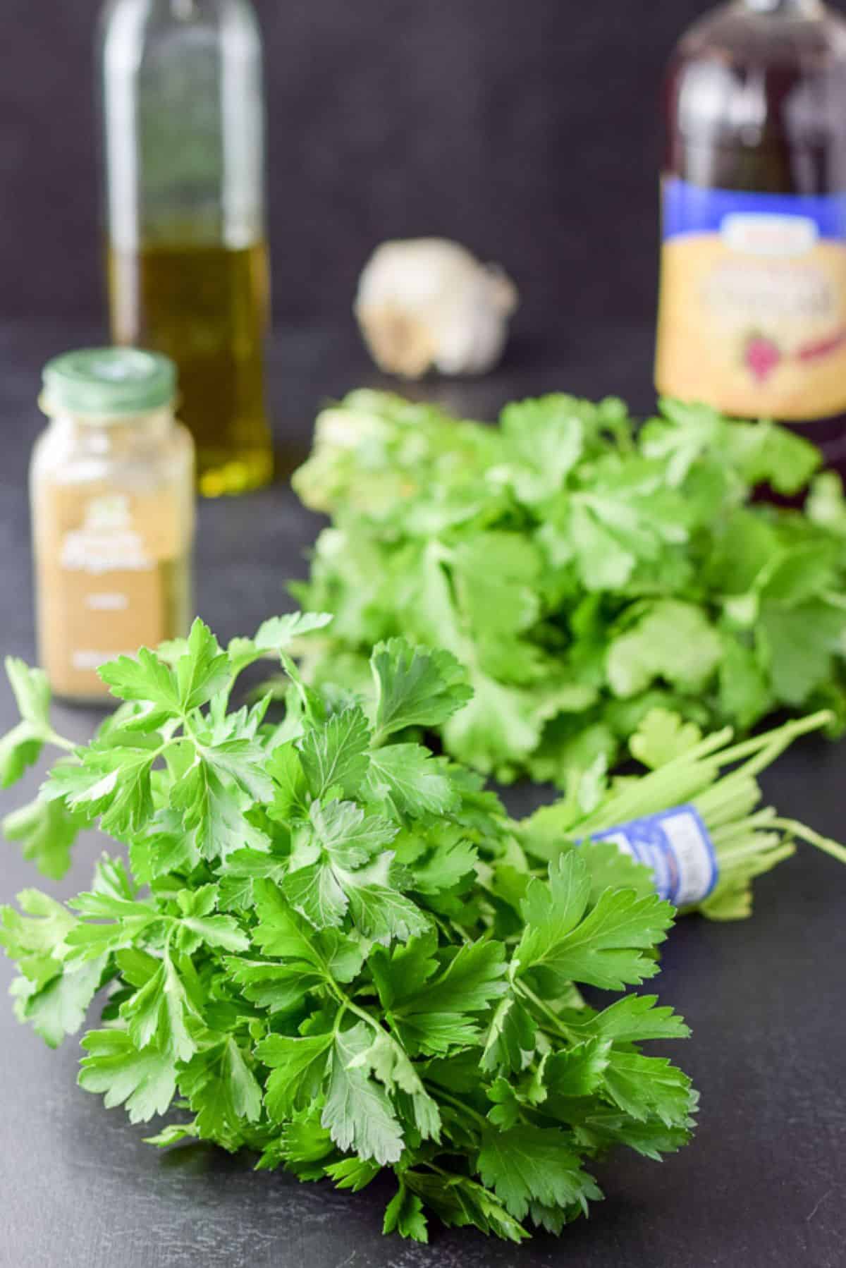 Cilantro, spices, oil, vinegar, and garlic on a table