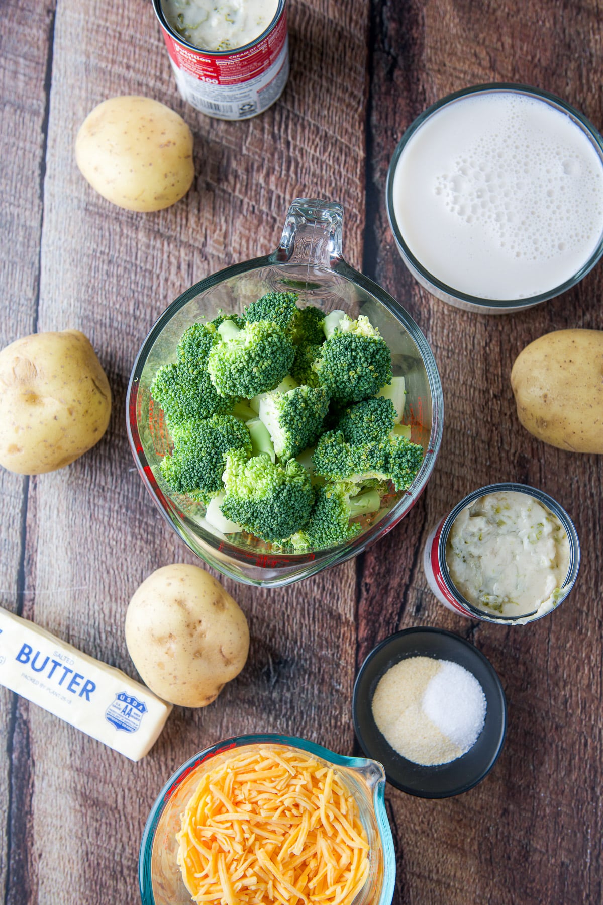 Overhead view of the ingredients - broccoli, pototoes, butter, shredded cheddar, spices, milk and canned soup