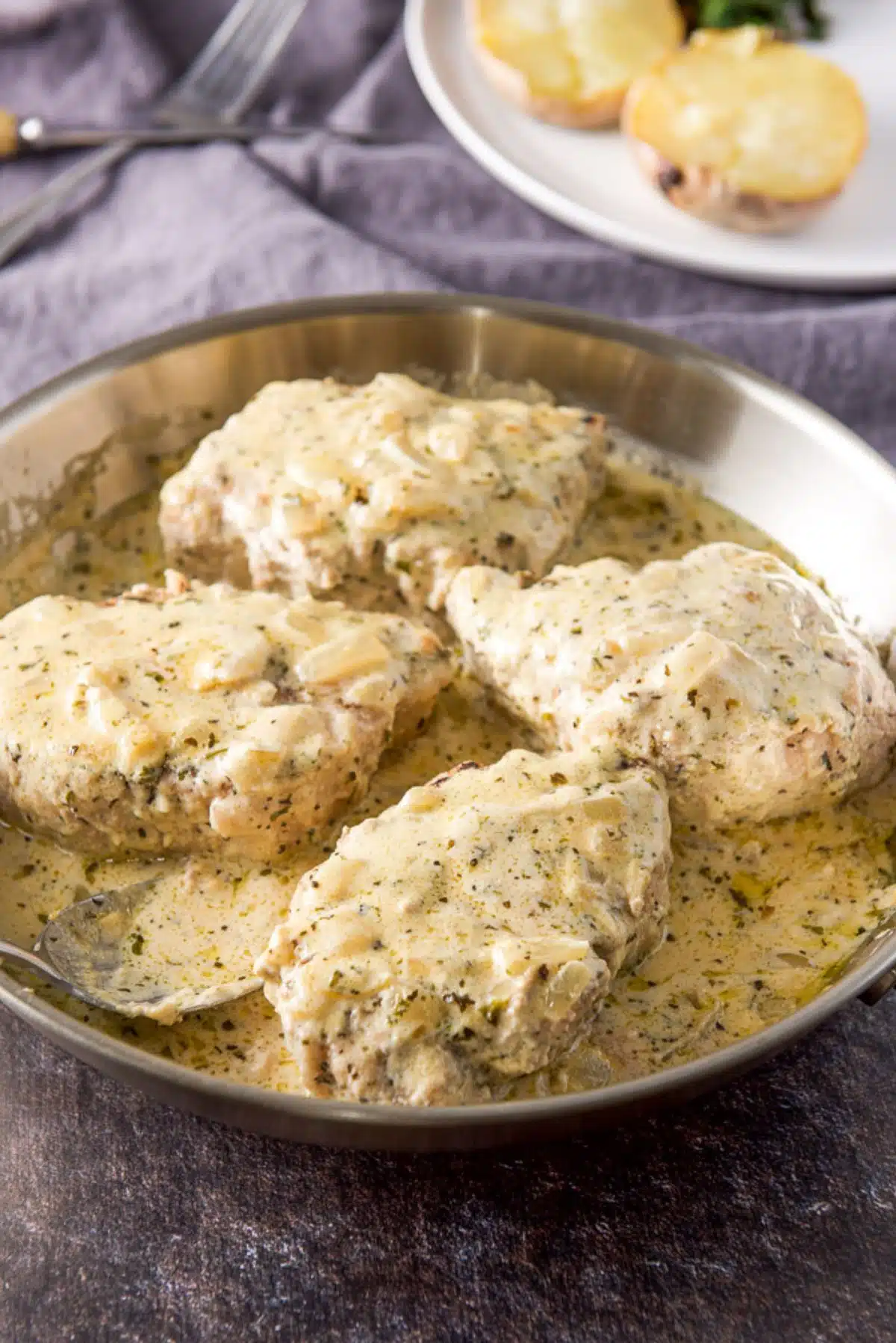 A pan of pork chops with sour cream sauce poured on