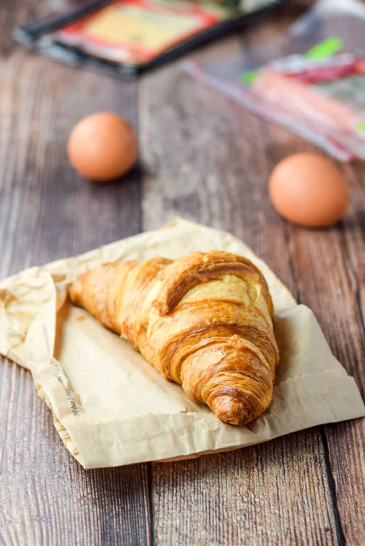 Croissant, eggs, ham and cheese on a wooden table