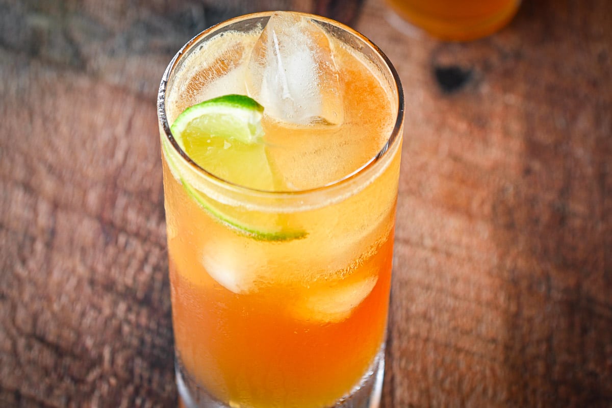 Horizontal photo of A tall glass with the cocktail with lime wedges