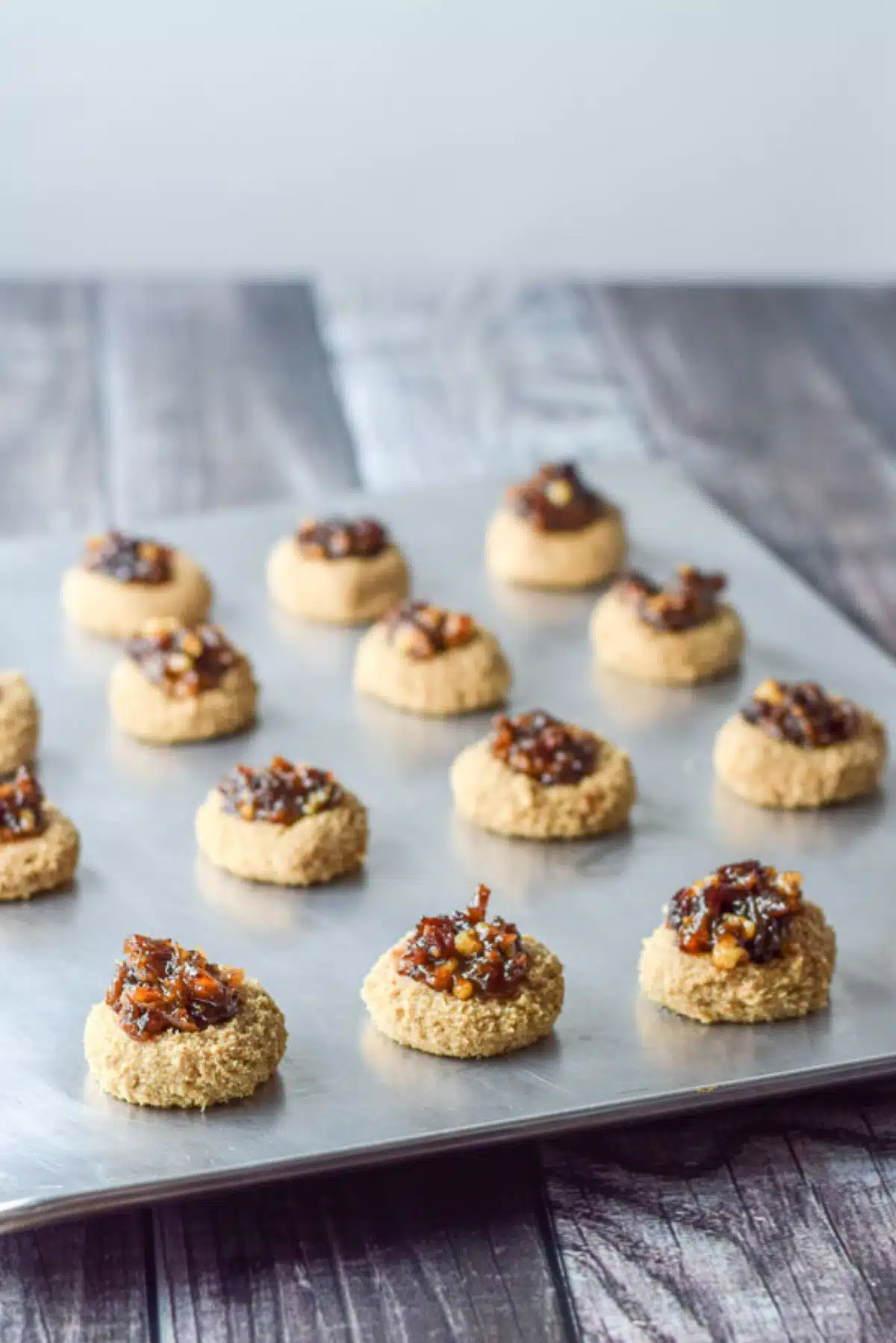 Dates and nuts put in the thumbprints on a cookie sheet