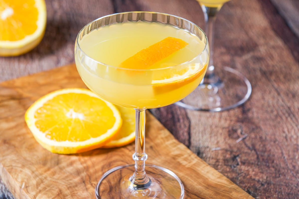 A wood table with the orange cocktail with orange slices on the board and table