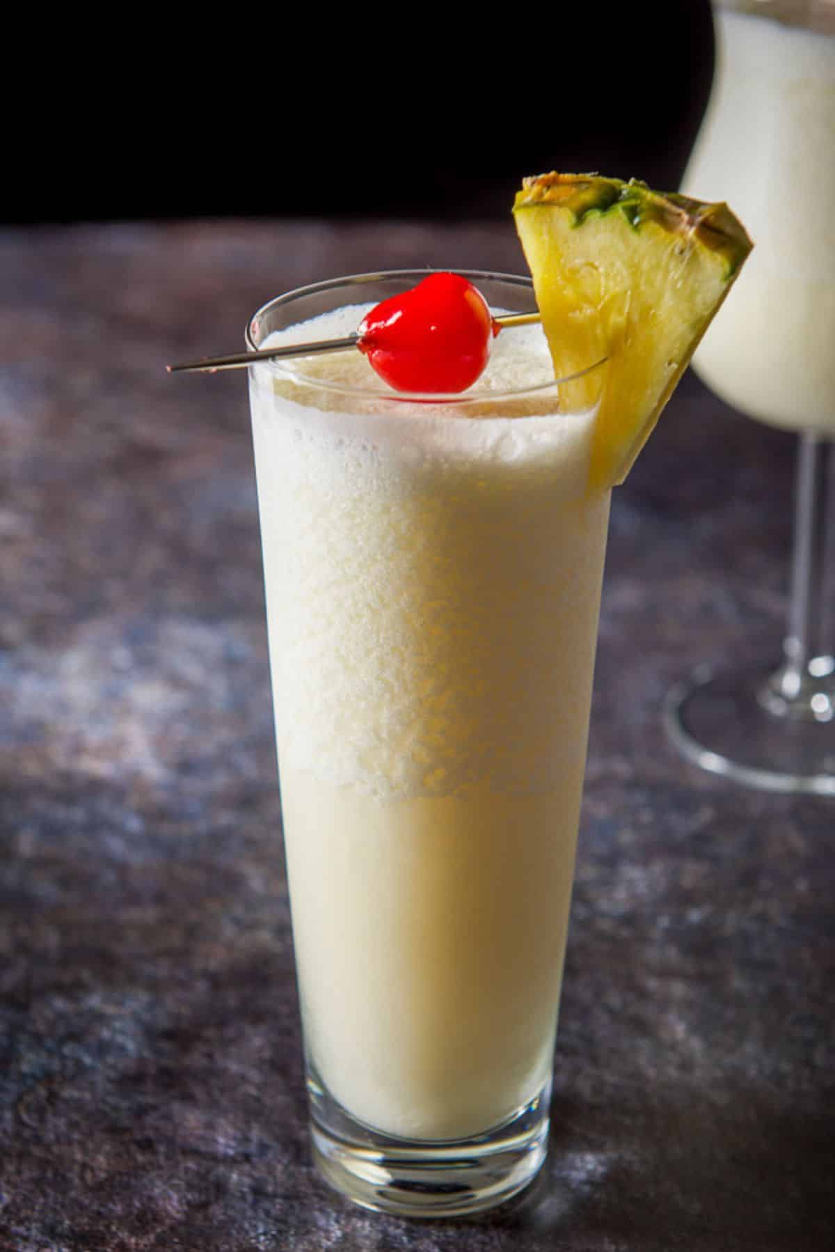 Tall glass of pina colada in front of the tulip glass