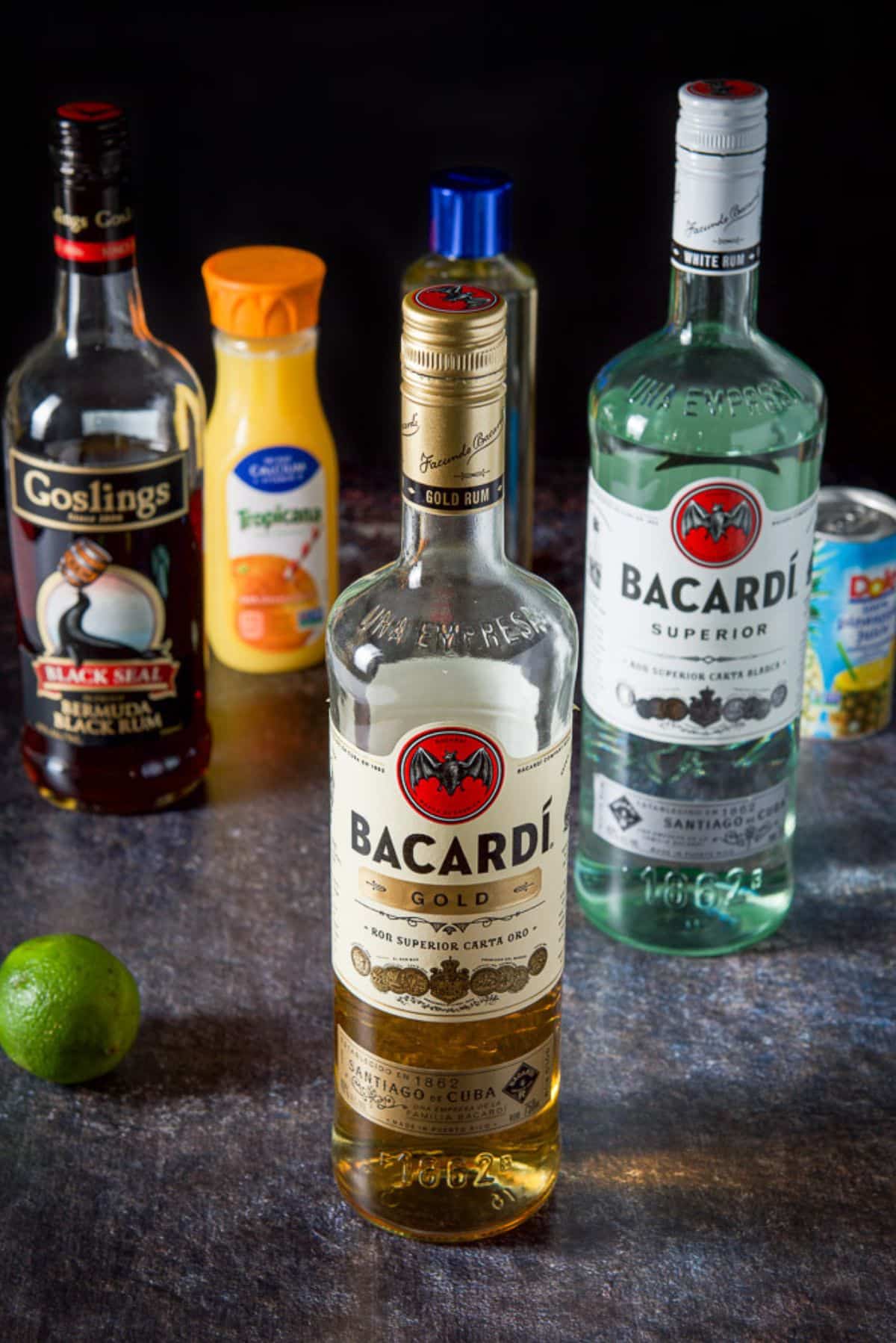 Gold, white and dark rum, lime, pineapple juice and simple syrup on a table