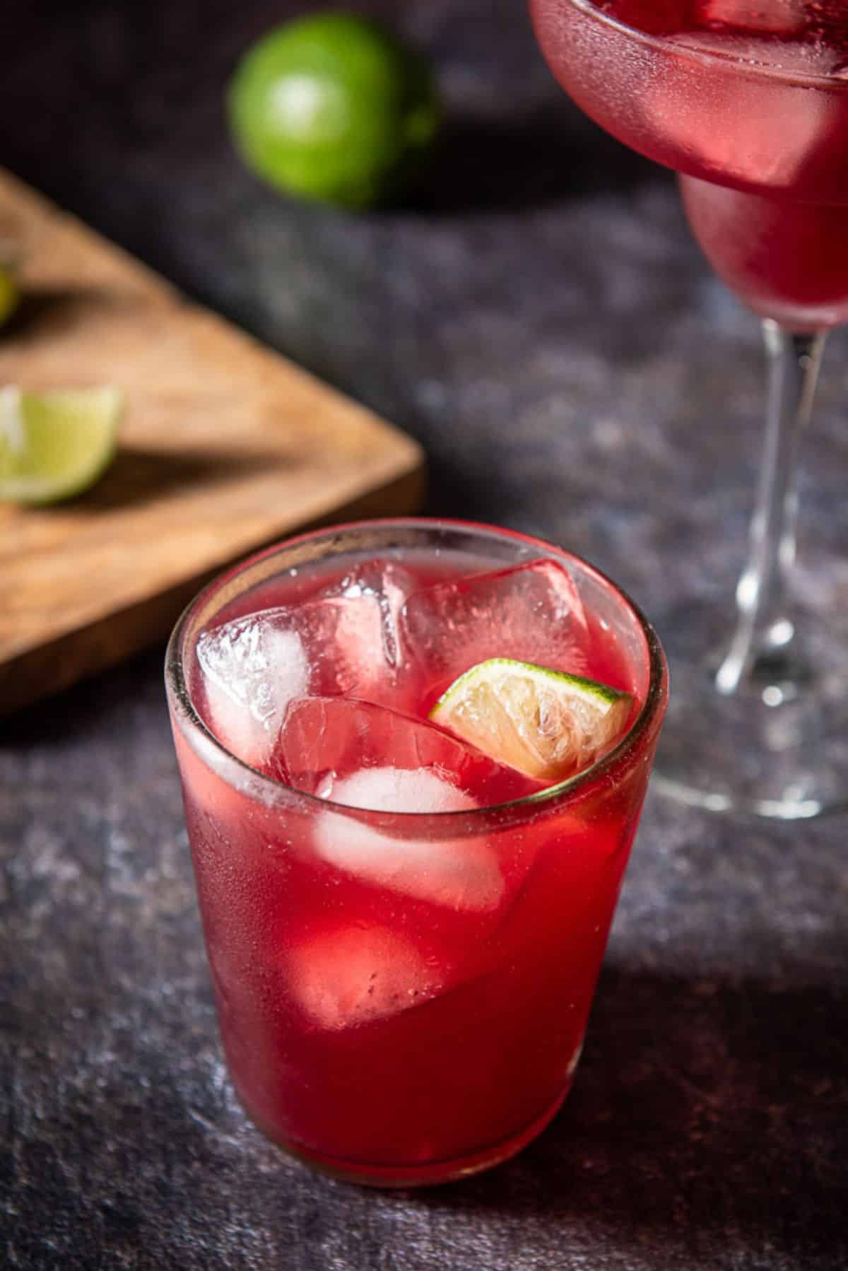 Close-up of the top of the pomegranate margarita in a short glass. There is a wedge of lime in it