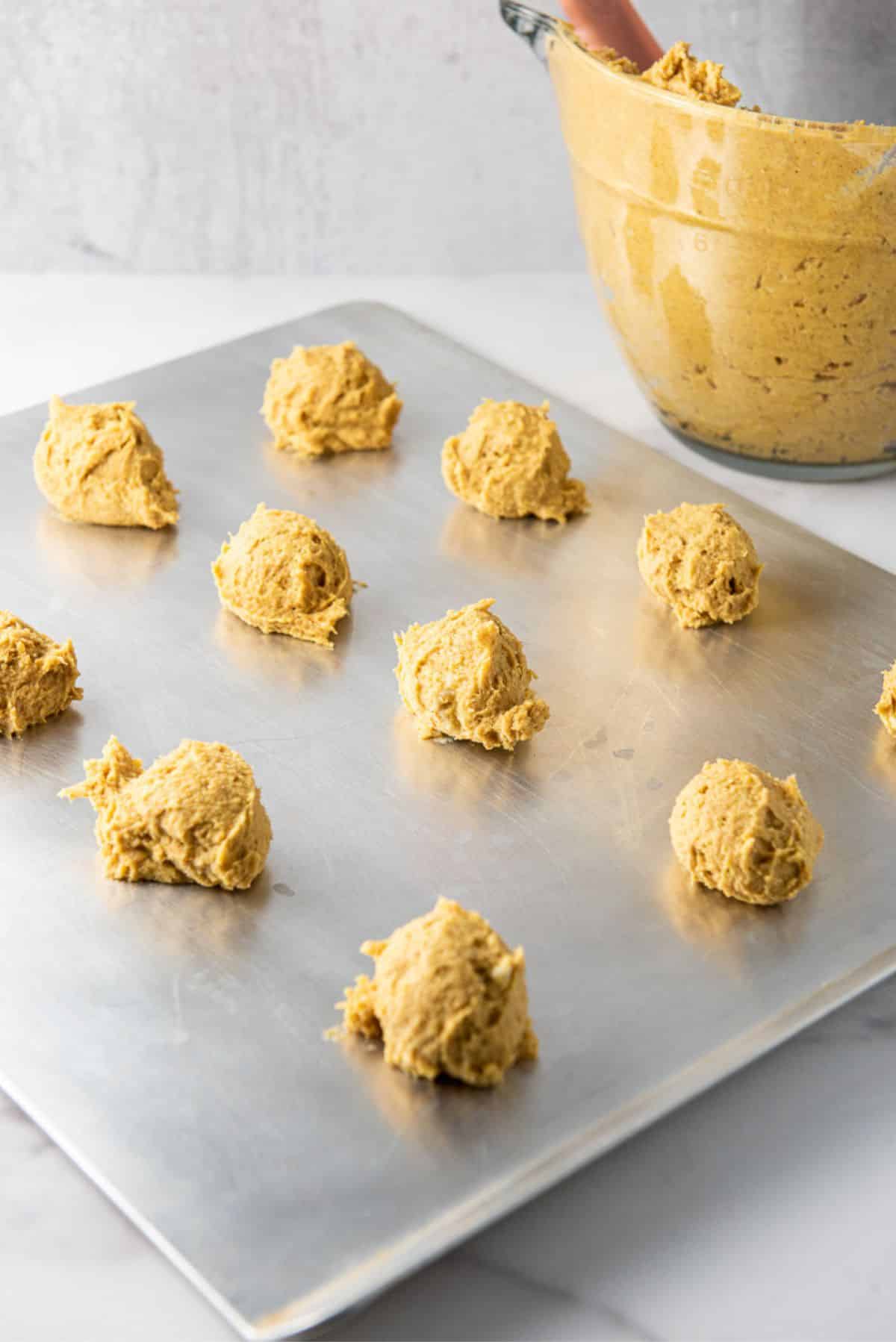 Balls of pumpkin cookie dough on a cookie sheet