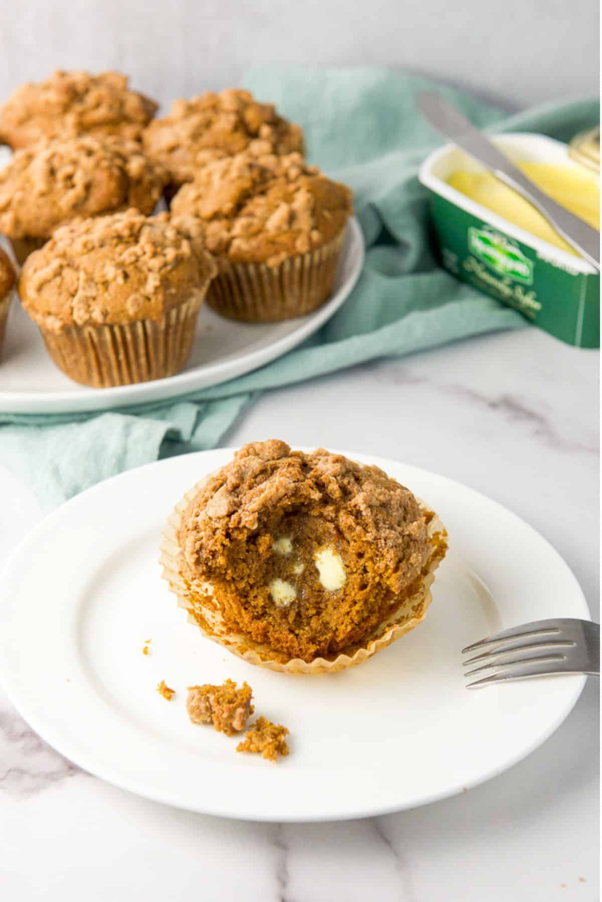A bite taken out of the muffin with butter slathered on it