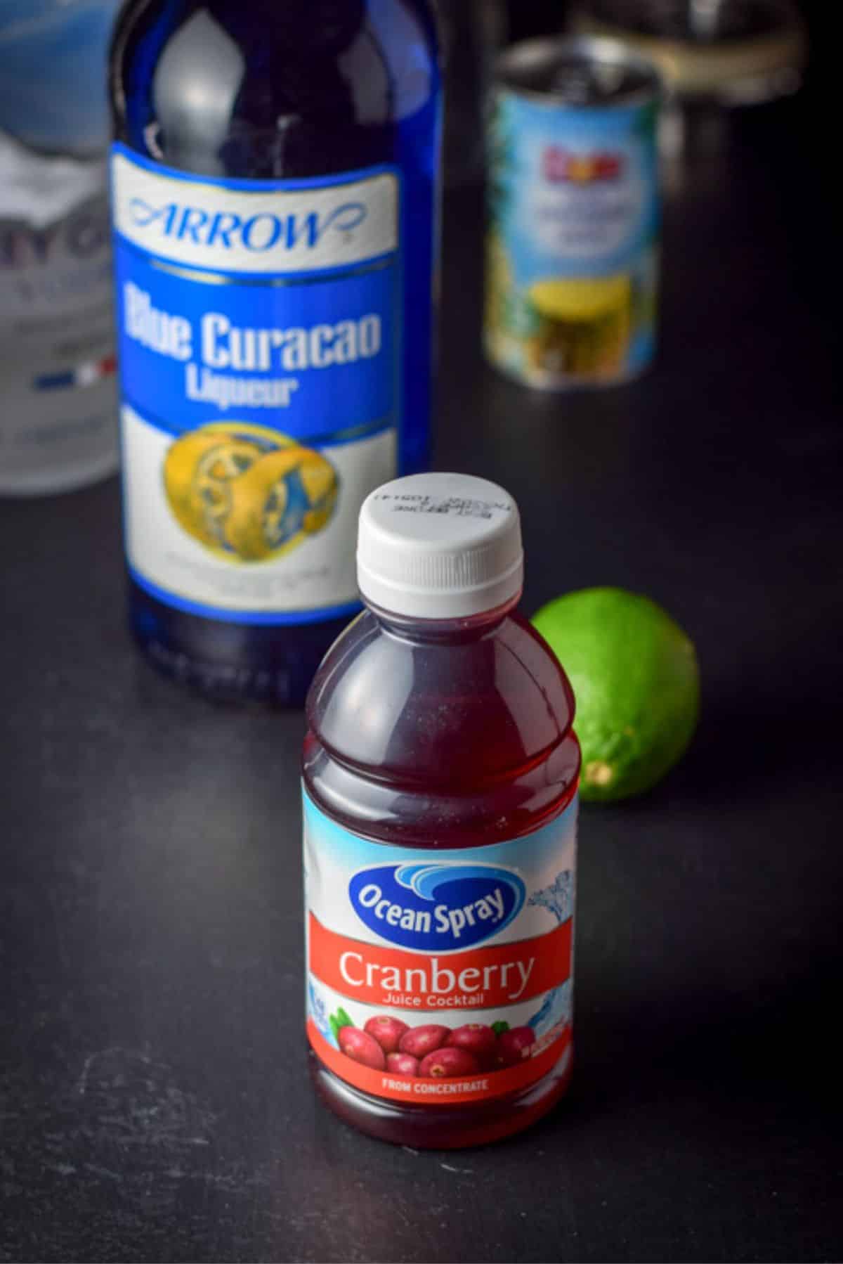 Cranberry juice, vodka, blue curacao, lime and pineapple juice on the table