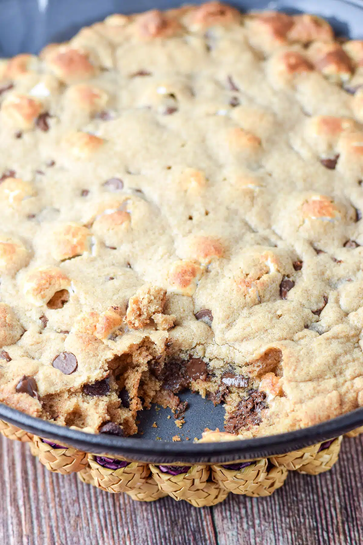 closeup of the chocolate chip cookie in the pan with a big chunk out of it