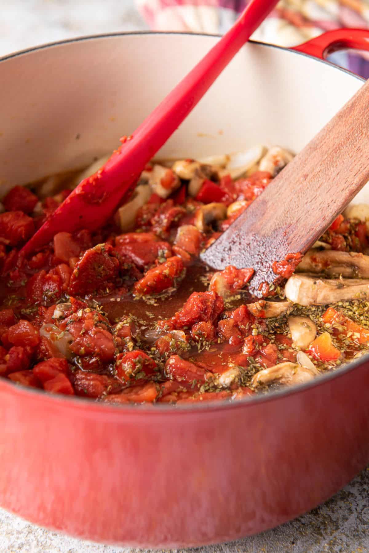 Herbs and diced tomatoes and tomato paste added to the pan